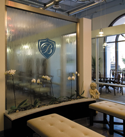 The new Beacham & Company office in The Medici building at The Plaza at Paces on Northside Parkway is filled with light and higlighted by 30-foot ceilings painted light blue. Other features include exposed aluminium ductwork, private offices with glass partitions and sliding doors, and a waterfall with the Beacham logo.